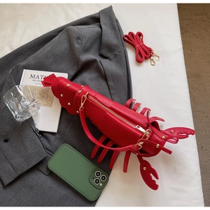Detailed view of red lobster shaped crossbody bag with gold rivets in a lifestyle setting