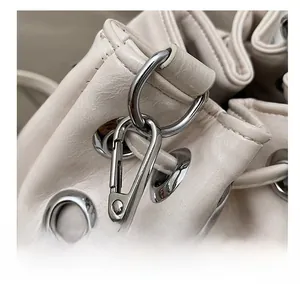 Detailed close-up of premium silver metal hardware and off-white leather bucket bag texture
