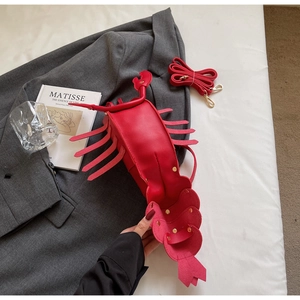 Artistic detail of a lobster-shaped crossbody bag with rivets and detachable strap