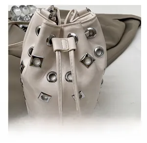Detail view of cream bucket bag showing silver metal grommets and drawstring closure