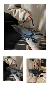 Detail of creative black lobster-shaped bag with gold rivets and PU leather texture