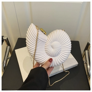 Close-up of white acrylic conch clutch bag with golden chain strap and spiral texture