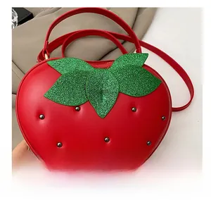 Détail du sac fraise avec texture en cuir rouge, feuilles pailletées vertes et clous en métal
