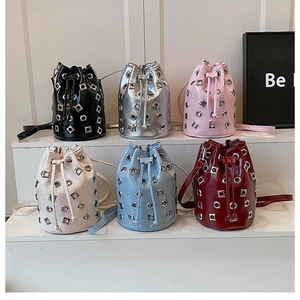 Détails des sacs seaux brillants à rivets en six coloris sur des marches blanches