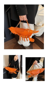 Detail of lobster shaped handbag with golden rivets and bright orange textured finish