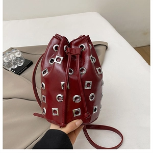 Détail d'un sac seau bordeaux avec clous métalliques et fermeture par cordon serrage
