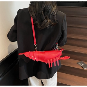 Close-up of a red lobster-shaped shoulder bag with metallic rivets on leather material