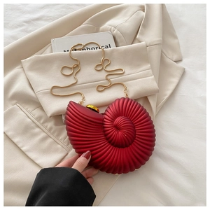 Detailed view of red shell-shaped clutch with gold hardware on aesthetic background
