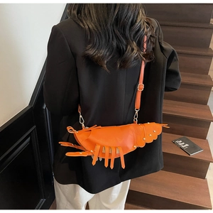 Detailed view of orange lobster-shaped crossbody bag with gold rivet accents on leather