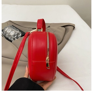 Détail du sac fraise rouge montrant la fermeture éclair dorée et la texture du cuir