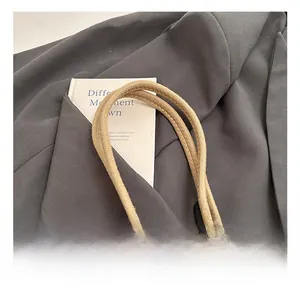 Detail showing the sturdy hand-woven rope handle of a beige contrast tote bag