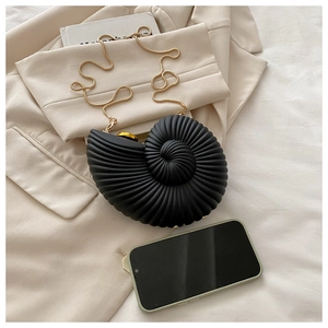 Macro view of shell-shaped acrylic clutch bag shown with smartphone for size comparison