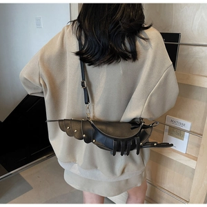 Close-up of black lobster shaped crossbody bag with gold rivets on model back
