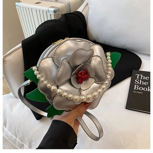 Detail of silver camellia-shaped evening bag with pearl handle and metallic petals