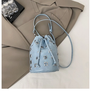 Vue de dessus d'un sac seau bleu clair à rivets métalliques sur veste marron
