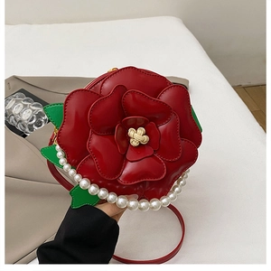 Close-up of a 3D red rose flower handbag with pearl handle and green leaf details