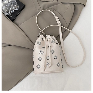 Vue détaillée d'un sac seau blanc cassé avec œillets métalliques sur une veste grise