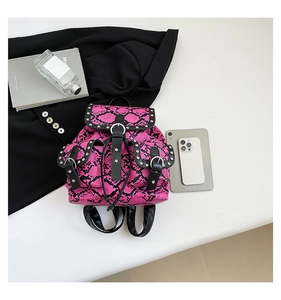 Flat lay of pink snake skin backpack with silver studs and black leather straps