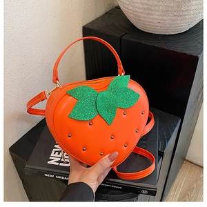 Détail du sac à main fraise orange avec feuilles vertes pailletées et clous métalliques