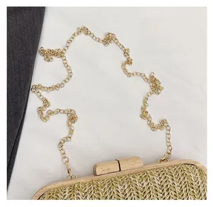 Detail of the woven straw texture and rectangular wooden buckle with gold chain strap