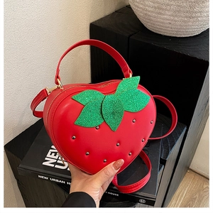 Détail du sac à main fraise rouge avec finition brillante et accents de feuilles pailletées