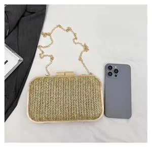 Detail view of woven straw clutch with wood frame and gold chain for size reference