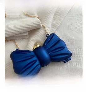 Détail de la pochette de soirée en forme de nœud bleu avec fermoir marbre doré