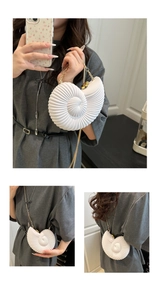 Detailed close-up of white acrylic conch shell clutch with gold chain and spiral texture