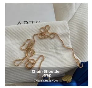 Détail de la bandoulière en chaîne dorée et du fermoir sur un petit sac bleu royal
