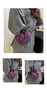 Detail of purple shell-shaped clutch bag with golden chain strap and textured surface