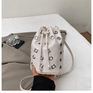 Détail d'un sac seau crème avec œillets métalliques argentés et cordons réglables