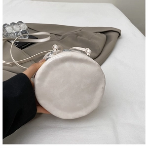 Détail du sac seau en cuir crème montrant la base circulaire et la texture du grain fin