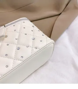 Detail of white quilted texture and silver rhinestones on the faux leather bag