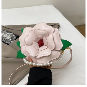 Close-up of pink flower-shaped bag with pearl chain and green leaf accents