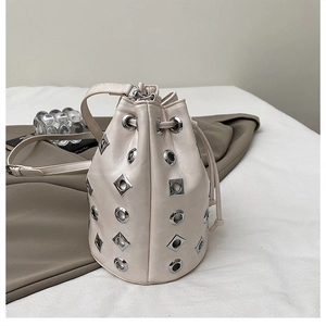 Détail du sac seau crème avec clous métalliques argentés et fermeture par cordon serrage
