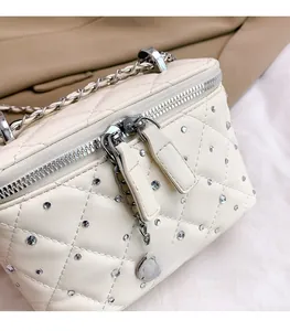 Close-up of quilted cream leather mini bag with sparkling rhinestones and silver chain