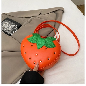 Détail d'un sac à bandoulière en forme de fraise en cuir orange avec des feuilles pailletées