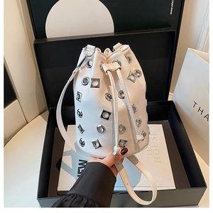 Détail d'un sac seau en cuir blanc avec des rivets métalliques et fermeture à cordon