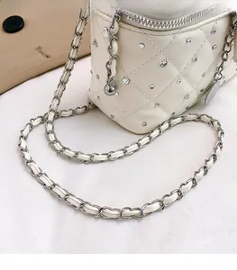 Detailed shot of white quilted shoulder bag with rhinestone embellishments and chain strap