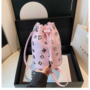 Sac seau rose à rivets dans sa boîte cadeau noire avec sac shopping blanc et livre
