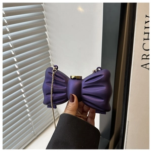 Détail d'une pochette violette en forme de nœud avec fermoir doré et bandoulière