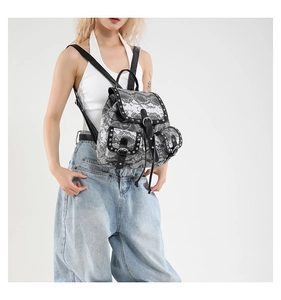 Detail of snake print backpack with silver studs and black leather straps on model