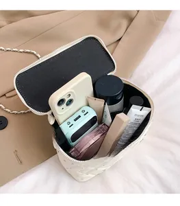 Detail view of white quilted crossbody bag interior with silver chain and daily essentials
