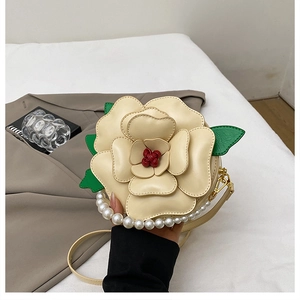 Detailed view of the layered camellia petal design and large pearl handle on the round bag