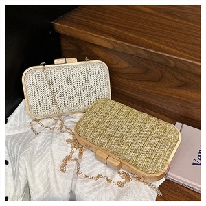 Detail of woven straw clutch bag with wooden frame closure and gold chain strap