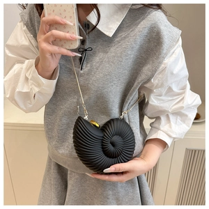 Detailed view of a black conch shell crossbody bag featuring a delicate gold chain strap