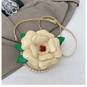 Detailed view of floral crossbody bag with 3D petals, green leaves and pearl trim
