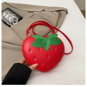 Détail du sac fraise en cuir rouge avec feuilles pailletées vertes et clous argentés