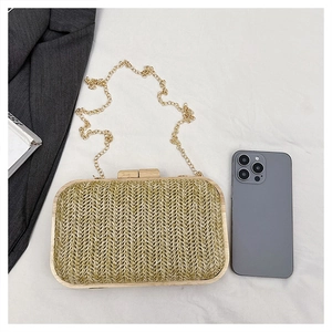 Top view of woven summer clutch bag with wooden clasp and chain next to mobile phone
