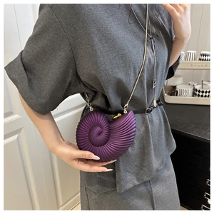 Macro detail of purple conch-shaped acrylic crossbody bag with spiral texture and gold chain